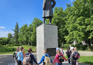 Zdjęcie przedstawia pomnik legionisty i dzieci stojące dookoła pomnika