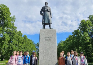 Zdjęcie przedstawia pomnik legionisty i dzieci stojące po obu jego stronach