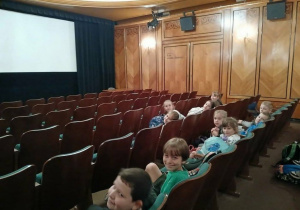 Zdjęcie przedstawia dzieci siedzące w sali kinowej łódzkiej filmówki