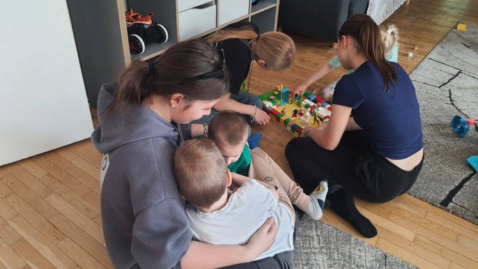 zdjęcie przedstawia uczni&oacute;w bawiących się z dziećmi z Domu Dziecka